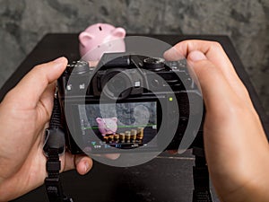 The photographer is intending to use digital camera take pictures of the pink piggy bank with coins bar graph photo