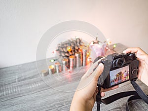 The photographer is intending to use digital camera take pictures of the pink piggy bank and party light photo