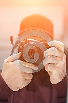 The photographer looks into the camera of the camera holding it in his hands. Soft focus. Photo with filter