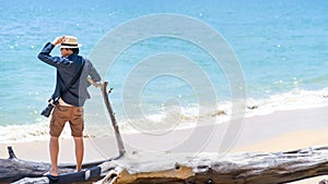 Photographer man standing on dead pine tree on the beach