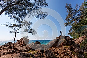 Photographer man standing on rock cliff have shooting session wild sea landscape