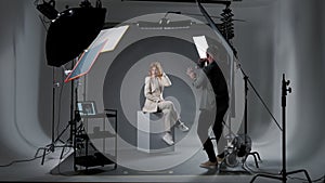 Photographer with model. Man with camera filming woman at professional photo studio