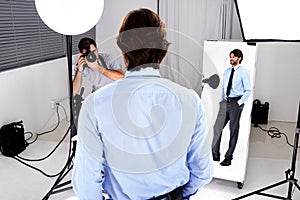 Photographer, model shoot and camera in studio, behind the scenes and equipment on set for advertising. Man, back and