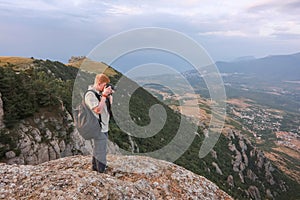 Photographer in mountains takes photos using reflex camera in Crimea