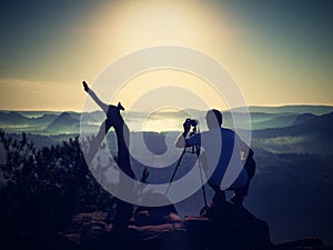 Photographer on peak of rock. Fall fogy landscape