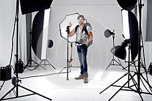 Photographer, portrait and lighting with equipment in studio for career, behind the scenes or electronics. Photography