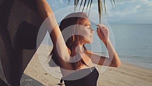 Photographer positions model on beach wearing black sunhat