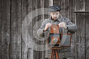 Photographer prepares for shooting and inserts film holder into retro large format camera. Concept - photography of the 1930s-