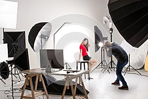 Photographer and pretty model working in modern lighting studio photo