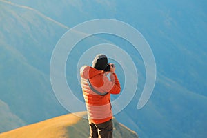 A photographer recording a mountain view in the morning.