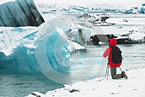 Photographer in red coat taking pictures of glacier ice