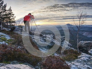 Photographer in red jacket and knitted cap stay with camera