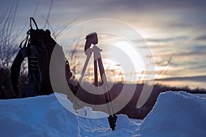 A photographer`s backpack and tripod on the snow at sunrise on a winter morning. Traveling and Relax Concept