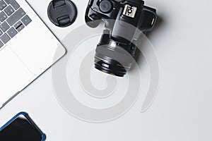 Photographer`s workplace on a white background. Modern laptop, digital camera, lens, battery, smartphone