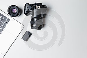 Photographer`s workplace on a white background. Modern laptop, digital camera, lens, battery, smartphone