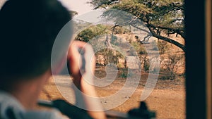 Photographer on safari in Africa takes pictures of a wild giraffe out of the car