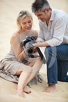 photographer with senior woman on location on sand dune