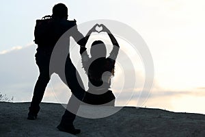 photographer shoots a girl with hands in the form of a heart against the sky