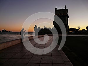 Photographer silhouette at sunset near Belem tower, famous tourist attraction in Lisbon, Portugal