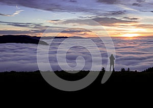 Photographer standing above fog on hill