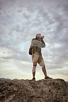 Photographer standing on a rock shooting during sunset