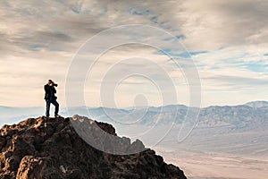 Photographer standing on a rock during sunrise at Dantes View