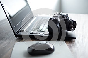 Photographer or stock photography concept, digital black camera near laptop on desk workstation