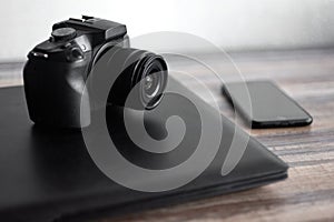 Photographer or stock photography concept, digital black camera near laptop and phone on desk workstation