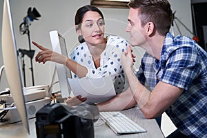 Photographer In Studio Reviewing Images From Photo Shoot On Computer With Female Client