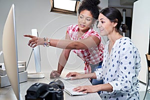 Photographer In Studio Reviewing Images From Photo Shoot On Computer With Female Client