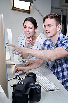 Photographer In Studio Reviewing Images From Photo Shoot On Computer With Female Client