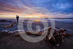 Photographer and sun set on black beach hokitika south island ne