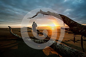 Photographer and sun set on black beach hokitika south island ne