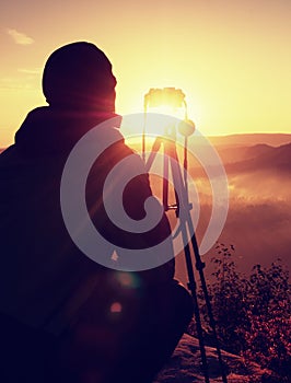 Photographer takes photos with camera on peak of rock