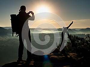 Photographer takes photos with camera on peak of rock