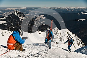 photographer takes pictures of male skiers with ski equipment climbing a snowy slope