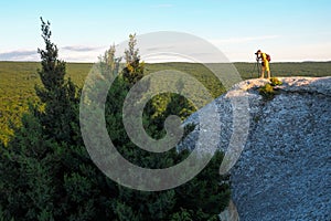 The photographer takes pictures of the scenery on the rock