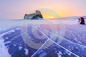 Photographer takes pictures winter ogoy island at sunrise in the ice of Lake Baikal, Russia