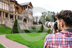 Photographer taking photo of beautiful house with camera outdoors