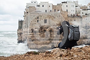 Photographer taking picture of a stormy sea in Polignano a Mare, Italy photo