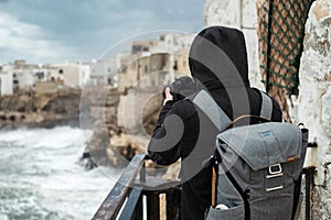 Photographer taking picture of a stormy sea in Polignano a Mare, Italy photo