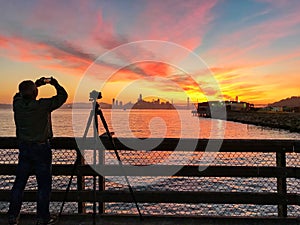 Photographer is taking a picture of sunset with San Francisco