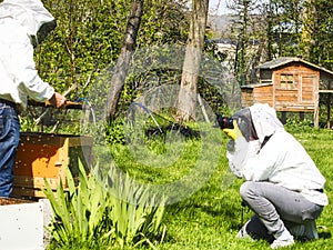 Photographer taking pictures of apiarist in garden