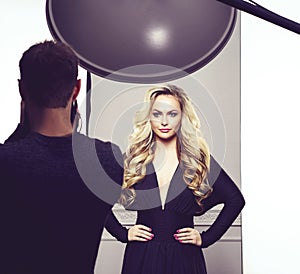 Photographer taking pictures of a beautiful model in studio.