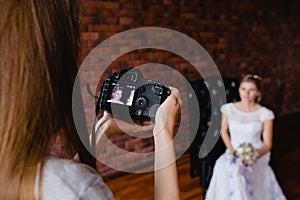 Photographer taking pictures the bride in the studio on a large leather armchair