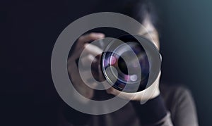 Photographer Taking Self-Portrait. Woman using Camera to Taking Photo. Dark Tone, Front View. Selective focus on Lense. Straight