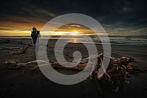 Photographer taking a sunset photograph at hotika beach southland new zealand