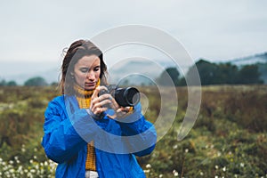 Photographer tourist girl in blue raincoat hold in female hands photo camera take photography froggy mountain, traveler shooting