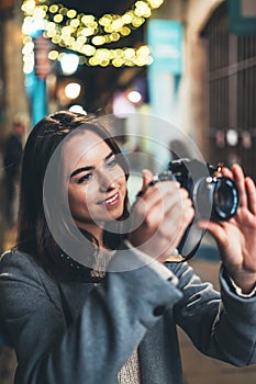 Photographer tourist girl with retro camera take photo on background bokeh light in evening city, Blogger photoshoot photo hobby