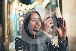 Photographer tourist girl with retro camera take photo on background bokeh light in night city, Blogger photoshoot photo hobby